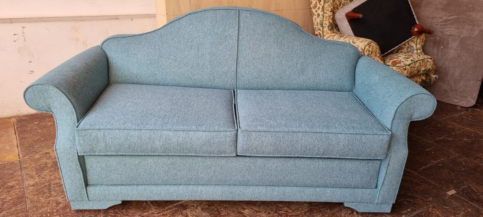 Sofá tapizado en azul celeste con respaldo decorativo. Tapicero cerca de mi